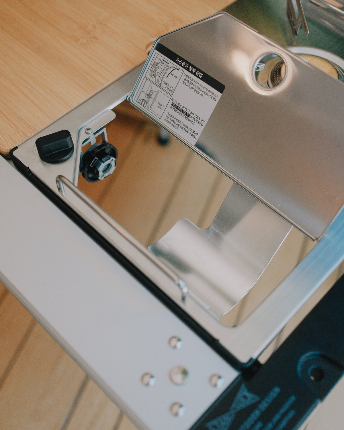 Kovea table stove in an IGT frame with the top plate lifted to show the gas connection