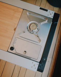 Overhead view of the Kovea stove sitting flush in an IGT frame beside a bamboo table