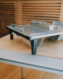 Low-angle view of the Kovea table stove raised on its legs over a bamboo table