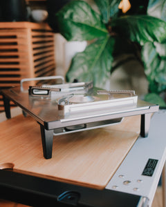 Side view of the Kovea Portable IGT Table Stove on its legs atop a bamboo IGT table