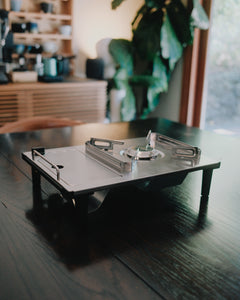 Kovea Portable IGT Table Stove on a dark wood table in a plant-filled room